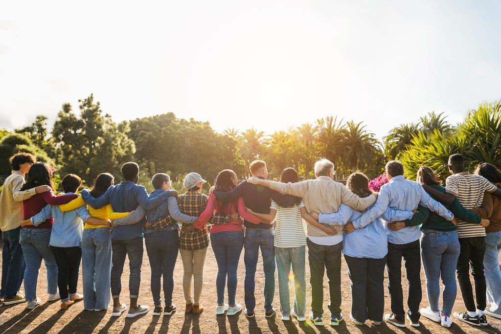 Gruppe von Menschen, die im Halbkreis steht und sich umarmt.
